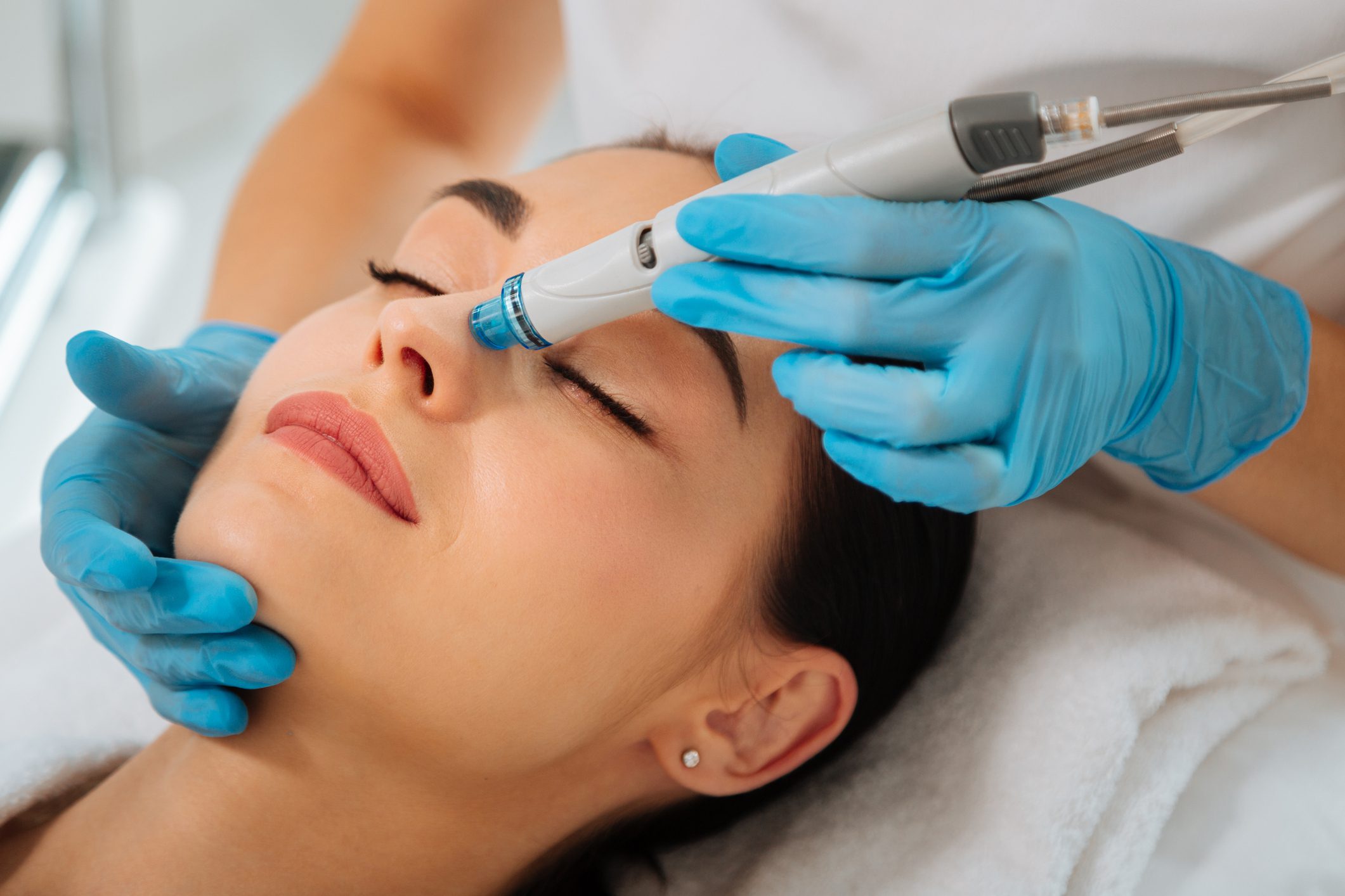 Woman receiving a facial treatment with a skincare device.