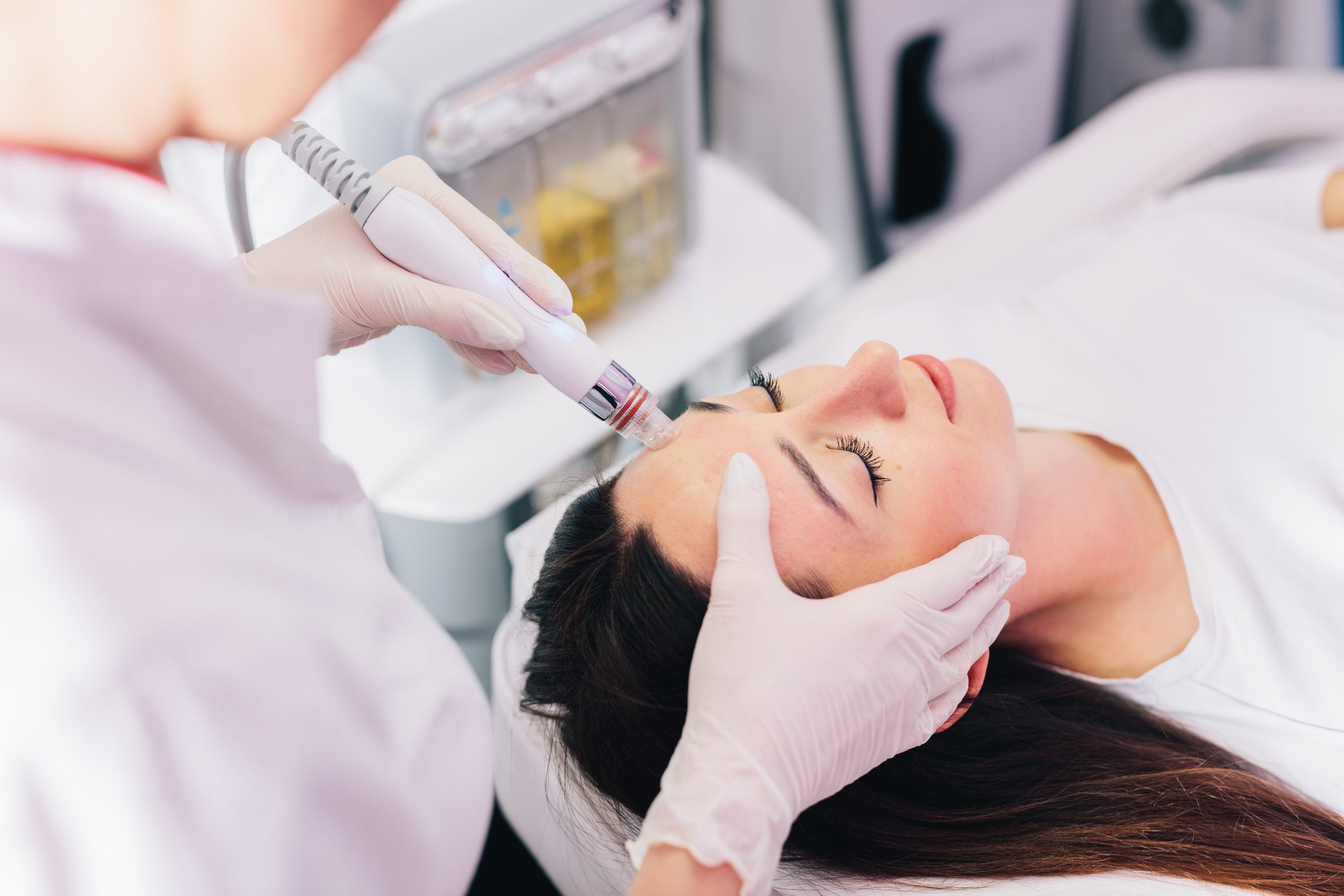 A woman receiving a facial treatment with a handheld device.