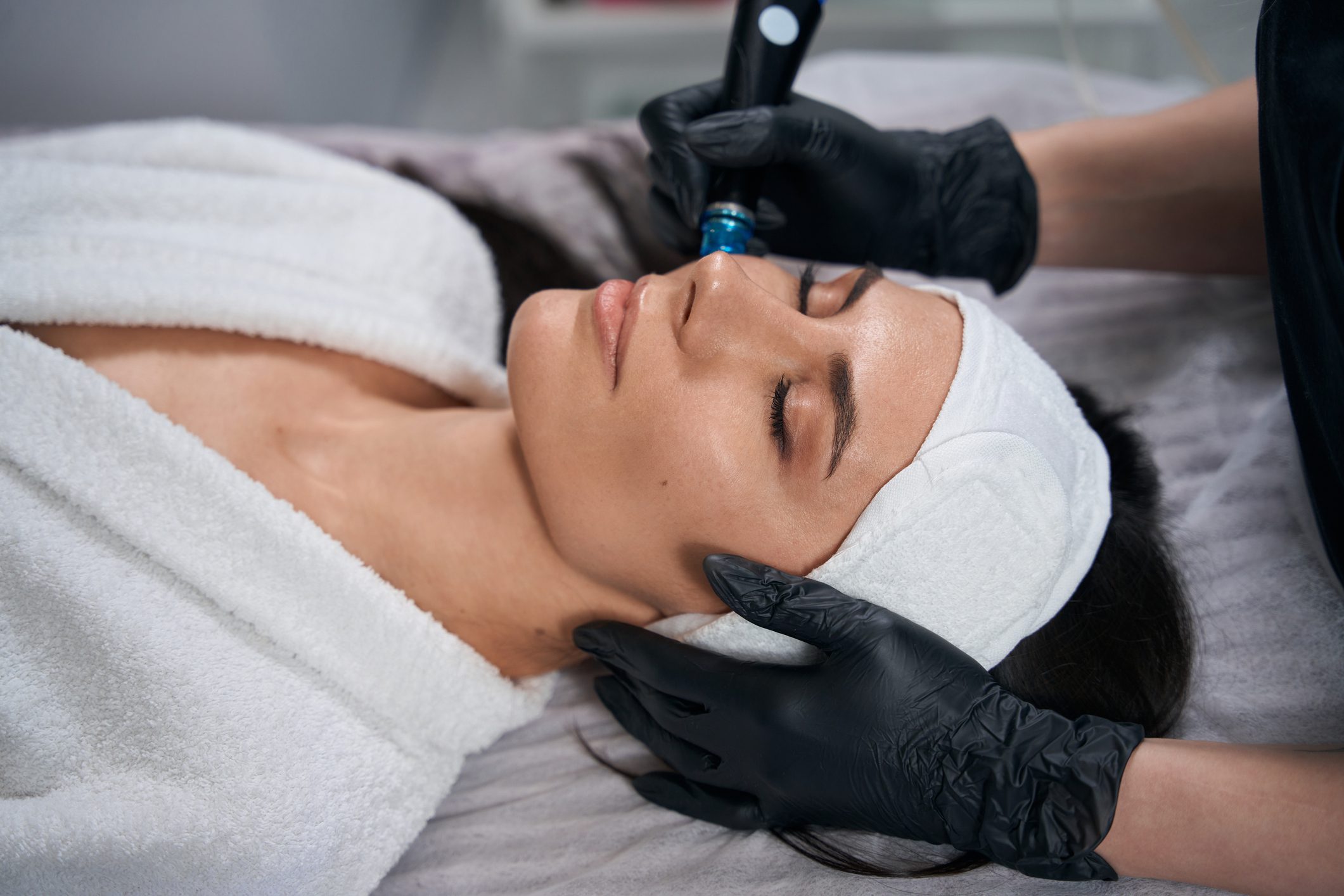 A woman receiving a facial treatment with a device in a spa setting.