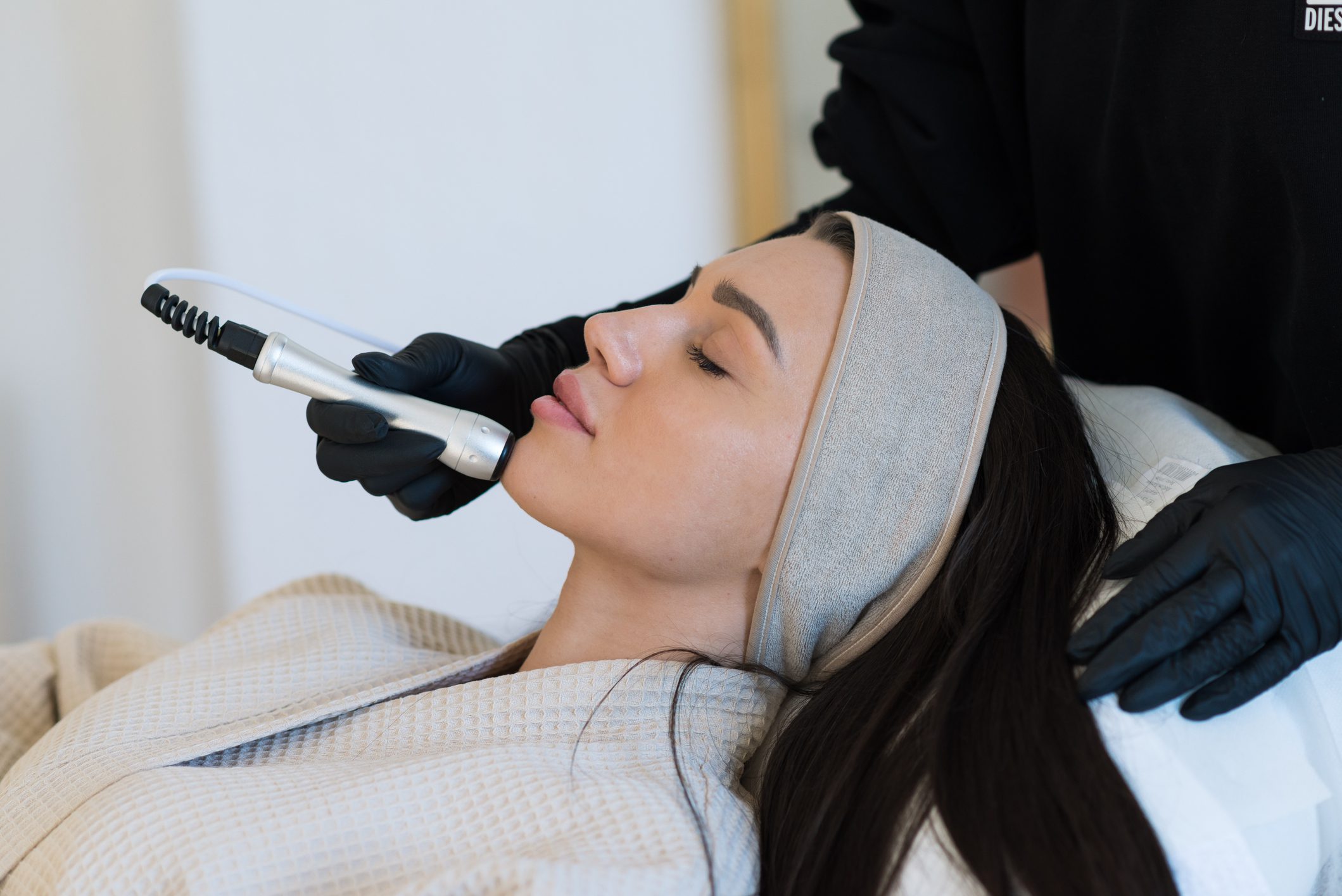 Woman receiving a facial treatment with a handheld device.