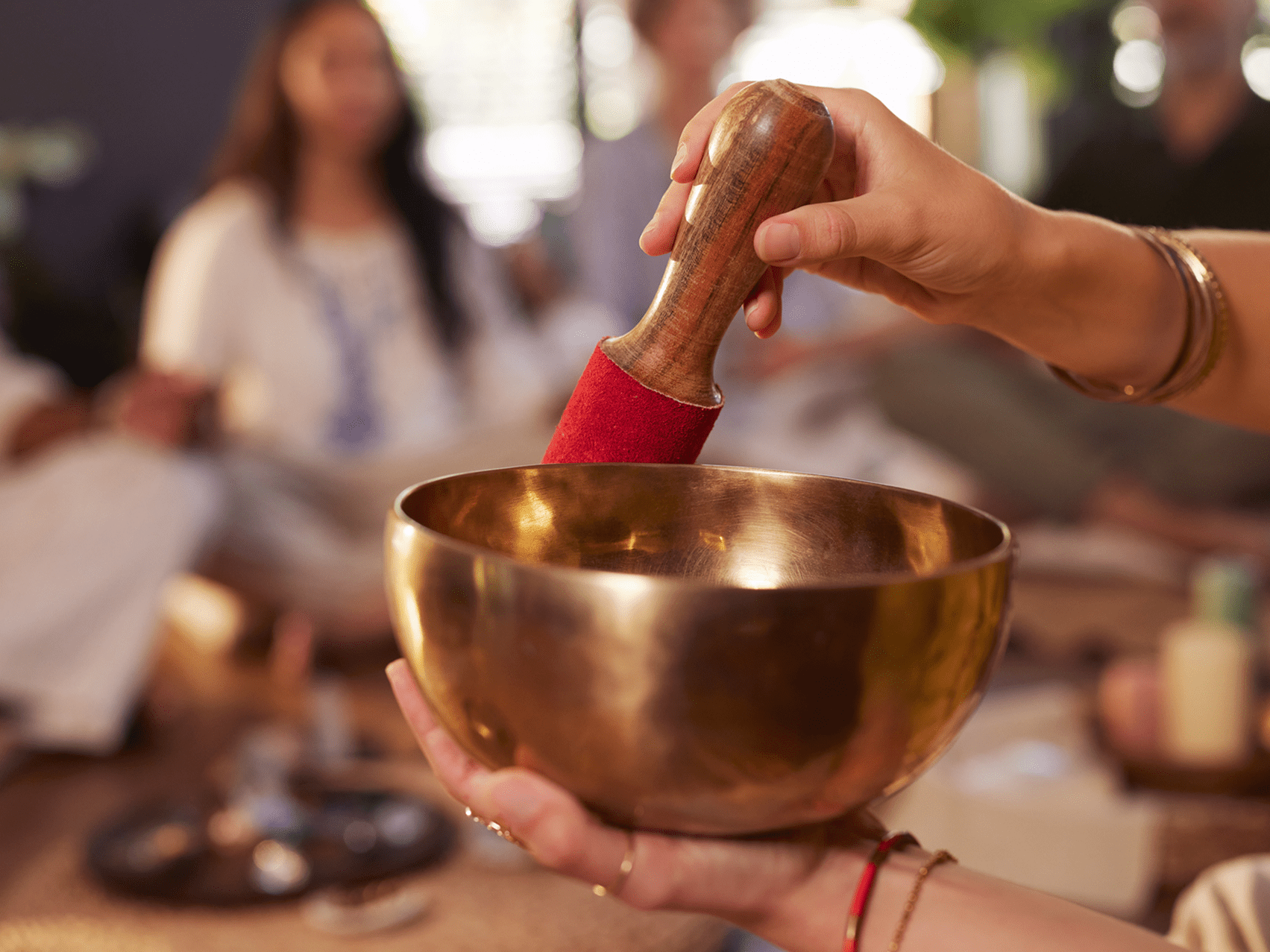 Person using a singing bowl with a wooden mallet.
