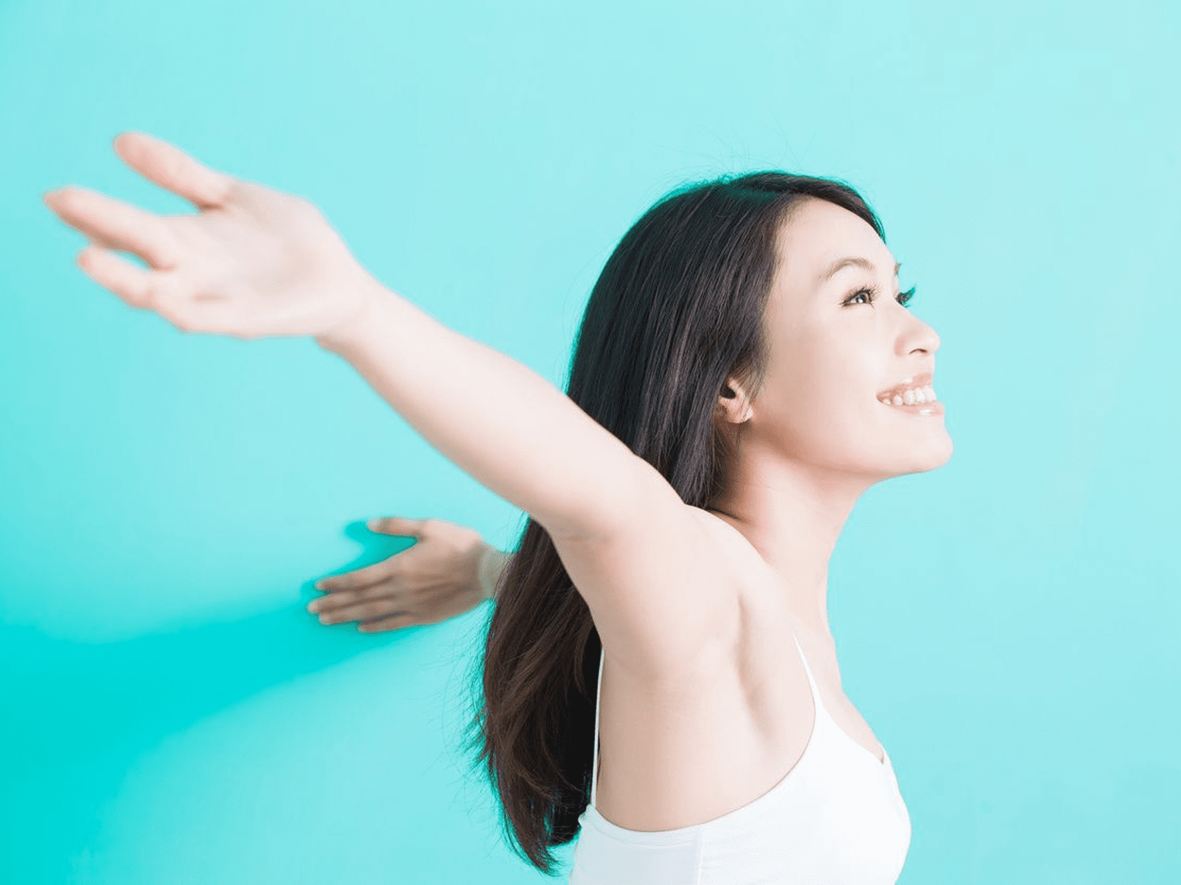 Happy woman enjoying freedom with arms outstretched against a blue background.