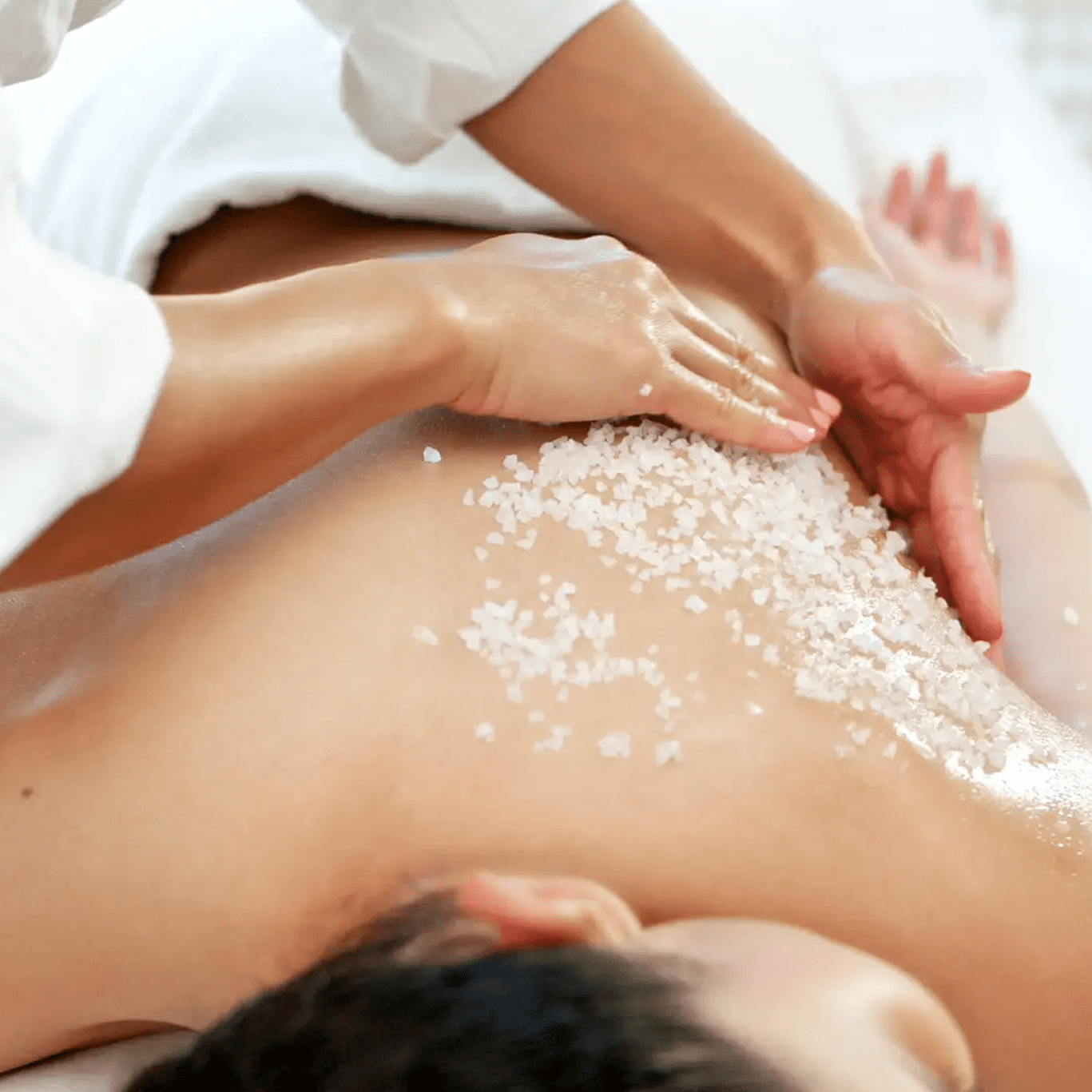 Person receiving a relaxing back massage with exfoliating salt.